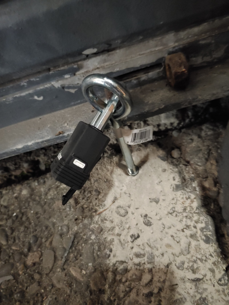 Padlock in concrete securing a liftup door. Vagrants were camping out